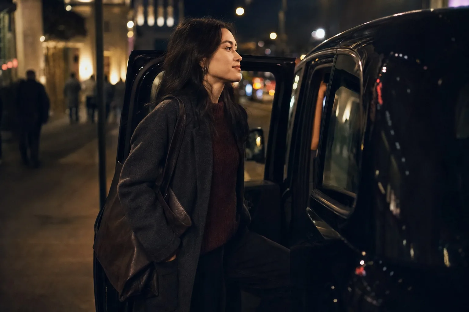 A young woman getting into a taxi at night on a city street